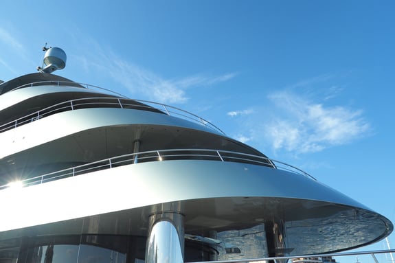 Close-up view of a modern luxury yacht with sleek curved decks under a clear blue sky.